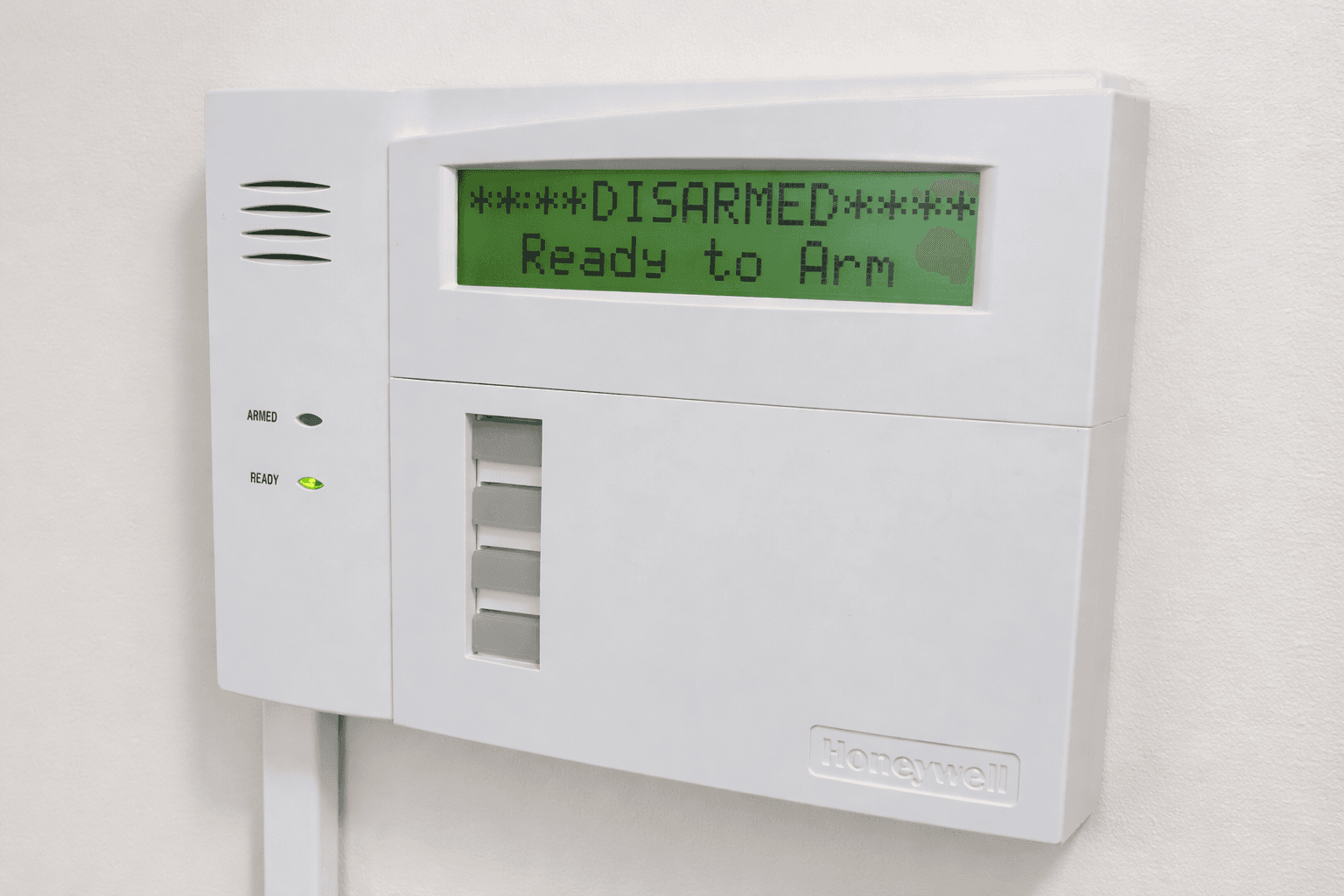 Honeywell security keypad on wall with green screen displaying DISARMED Ready to Arm status.